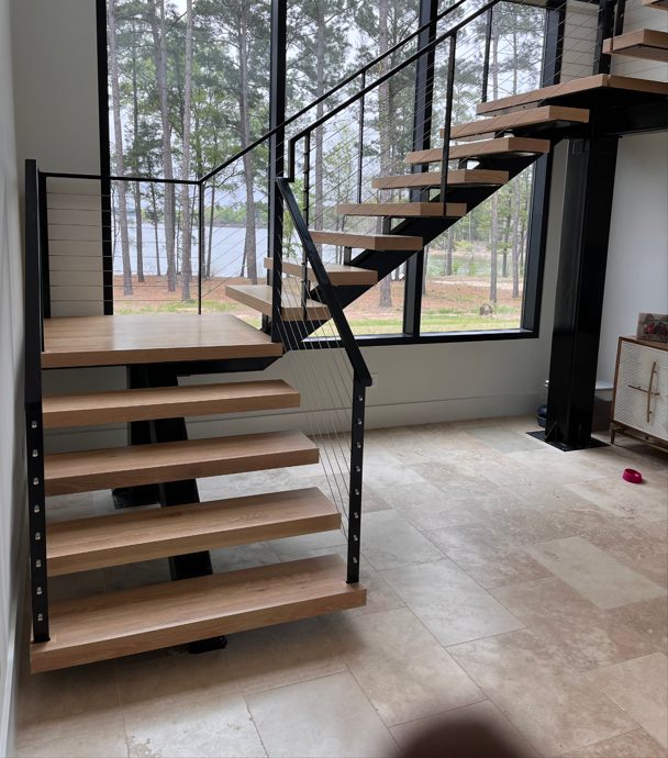 A sleek black metal frame with minimalist cable railings, providing a modern and open aesthetic that complements the floating wood steps.