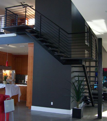 Space saving center support staircase provides access to loft and gives retro styling to this kitchen / living area.